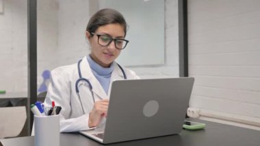 Hintli genç doktor hastayla görüntülü konuşma yapıyor.