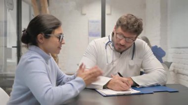 Orta yaşlı Doktor Kadın Hasta Reçetesi Yazıyor