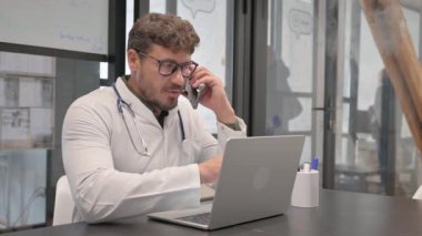 Male Doctor Talking on Phone in Clinic