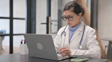 Dizüstü bilgisayar kullanırken kameraya bakan Hintli kadın doktor