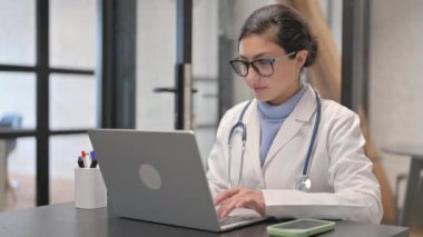 Başparmakları havada, kameraya bakan Hintli kadın doktor