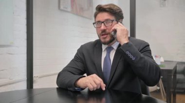 Orta yaşlı İşadamı Müşteriyle telefonda konuşuyor