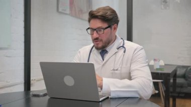 Orta yaşlı doktor video sohbetinde hastayla konuşuyor.