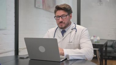 Bilgisayar Kullanılırken Kameraya Bakan Orta Yaşlı Doktor