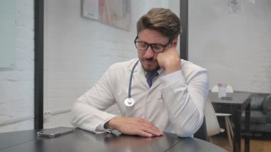 Klinikte otururken Orta yaşlı Doktor Uyuyor
