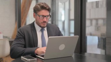 Dizüstü bilgisayarında Baş Ağrısı Yazan Olgun Yetişkin İş Adamı