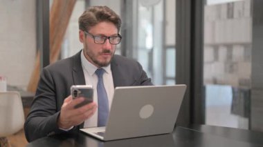 Yetişkin İş Adamı Bilgisayarda Telefon ve Daktilo Kullanıyor