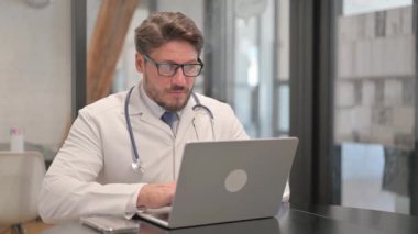 Young Doctor Looking at Camera while Using Laptop