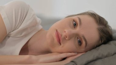 Yatakta yatarken kameraya bakan Ciddi Kadın 'ın yakın çekimi.