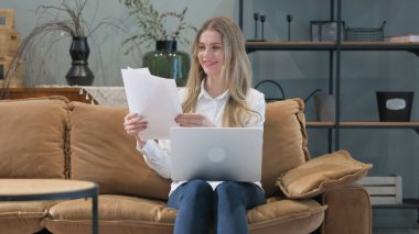 Heyecanlı Genç Kadın İş Raporu Okuma ve Dizüstü bilgisayar Kullanma