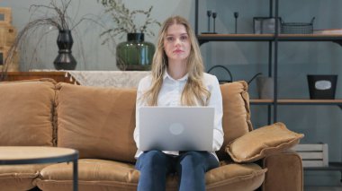 Evde Dizüstü bilgisayar kullanırken Genç Kadın Kameraya Bakıyor