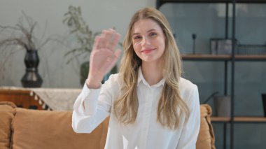 Eve Hoşgeldiniz demek için el sallayan genç kadın portresi.