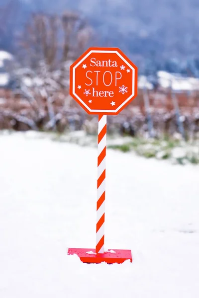 Christmas sign with text \'Santa Stop here\' in snowy landscape