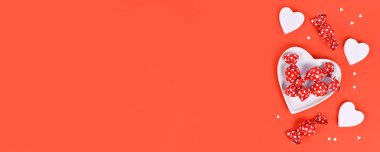 Sevgililer günü şekeri, konfeti ve kalp şeklinde plaka ile kırmızı arka planda fotokopi alanı