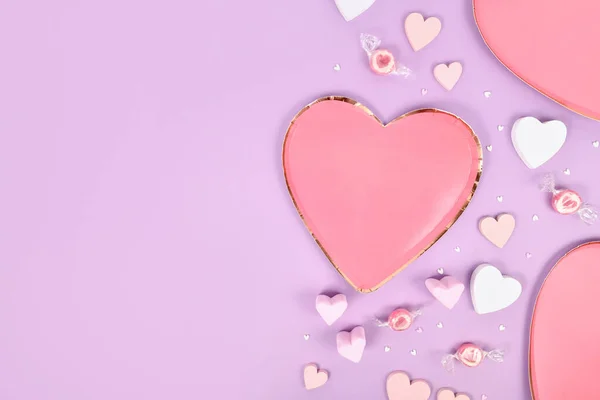 stock image Pastel colored Valentine's Day flat lay with heart shaped plates, heart ornaments and candy on violet background 