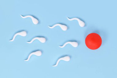 Mavi zemin üzerinde yumurta hücresine doğru yüzen soyut sperm hücreleri