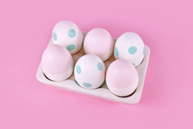 Pastel boyalı Paskalya yumurtaları pembe arka planda yumurta tepsisinde