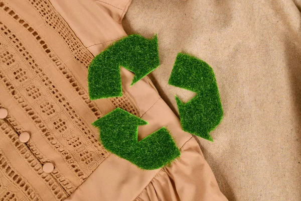 Concept for environmental friendly produced clothing with recycling arrow symbol made out of grass