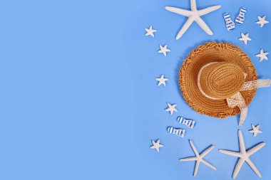 Beyaz denizyıldızı, yaz hasarı şapkası ve mavi arka planda sandaletler.