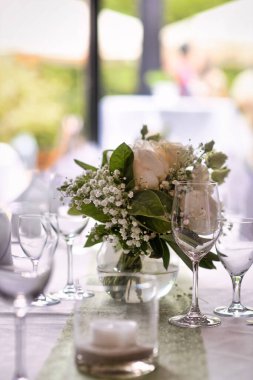 Şarap kadehleri ve çiçek buketleriyle düğün masası.