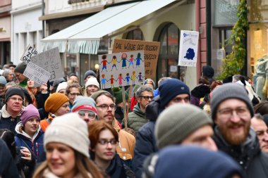 Heidelberg, Almanya - 12 Şubat 2025: Aşırı sağcıları protesto etmek için kalabalıkta renkli insanların çizildiğini gösteren tabela tutan kişi 