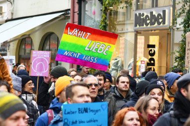 Heidelberg, Almanya - 12 Şubat 2025: Gökkuşağı tabelasını elinde tutan kişi aşırı sağcılara karşı kalabalıkta 