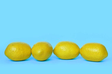 Mavi zemin üzerinde dört limon meyvesi ve kopyalama alanı