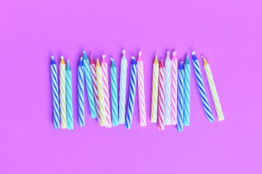 Parlak pembe arka planda renkli doğum günü mumları