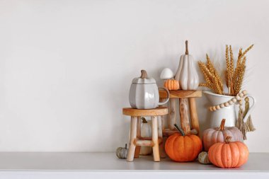Mevsimlik sonbahar dekorları ahşap stantları, balkabakları ve beyaz duvarın önünde tahıllı vazolar
