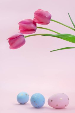 Pink tulips over painted eggs. Easter. Vertical. Copy space