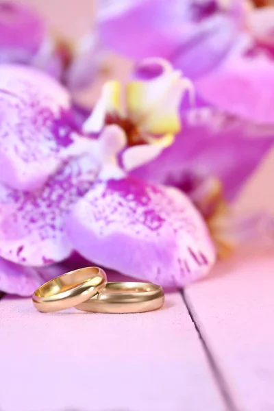 Anneaux Mariage Dorés Avec Orchidées Violettes Sur Table Bois Rose — Photo