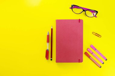 Kırmızı kapalı günlük, kalemli, kalemli, kalemli ve gözlüklü defter. Düz yatış, okula dönüş, öğrenme, iş, planlama. Boşluğu kopyala