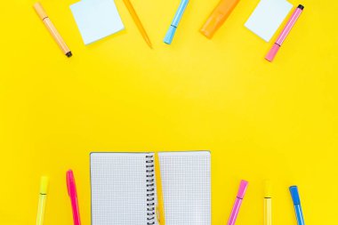 Sarı arkaplandaki renkli çıkartmaların yanına kalem, kalem ve boş sayfalar ile defter aç. Okula dönelim. Boşluğu kopyala