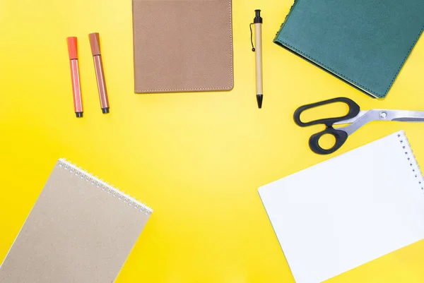 Back to school. Education flat lay. Business layout. Mock up, notepads, pen, marker, scissors on yellow background. Workplace. Copy space
