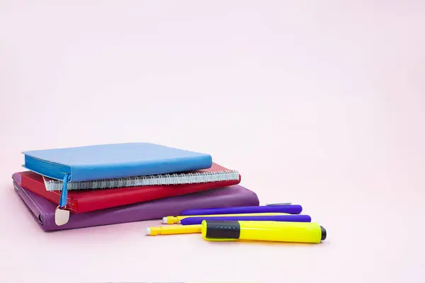 ピンクのテーブルの上にペンとマーカーでノートパッドのスタック 学校に戻る スペースのコピー — ストック写真
