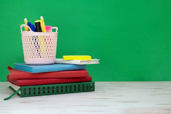 白いテーブルの上にマーカーの鉛筆ケースとノートパッドのスタック 緑のボード 学校に戻る スペースのコピー — ストック写真