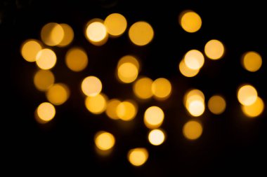 Siyah arka planda sarı ve kahverengi ışıkların çözünmüş hali. Bulanık bokeh, üstüste koy. Noel, yeni yıl, tatil