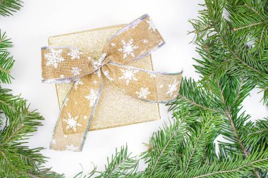 Beyaz arka planda köknar dalları olan gümüş yay içeren altın kutu. Noel, yeni yıl posteri, bayram afişi, tebrik kartı, doğum günü, sevgililer günü, indirim. Boşluğu kopyala