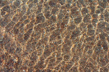 Denizin şeffaf dokusu, temiz suyun göl yüzeyi kumlu çakıl taşının altında dalgalanmalar. Soyut yaz geçmişi. Boşluğu kopyala