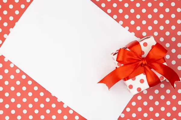 Red polka dots gift or present box with bow with paper on pattern background. Birthday, Valentine's, Mothers's and Women's day, holiday. Copy space