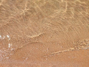 Yukarıdan gelen soyut kahverengi kumsal yaz tatili arka planında dalgalı ve güneş ışınlı berrak su. Doğa
