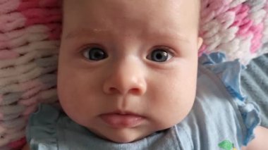 Beyaz bir battaniyeye uzanmış mavi gözlü şirin bebek.