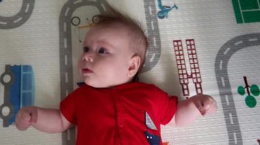 Bebek çocuk odada oynuyor, aşağıya bakıyor.