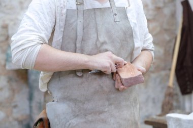 Genç heykeltıraşın elleri afilando una de sus herramientas 'ın atölyesine yakın.