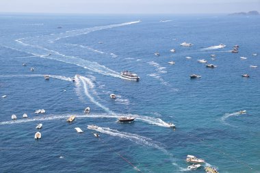 Deniz manzaralı, beyaz bir iz bırakan bir sürü tekne var.