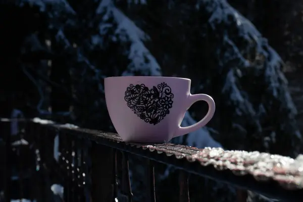 Cup of coffee with forest surroundings, snow, cold weather, mountain landscape