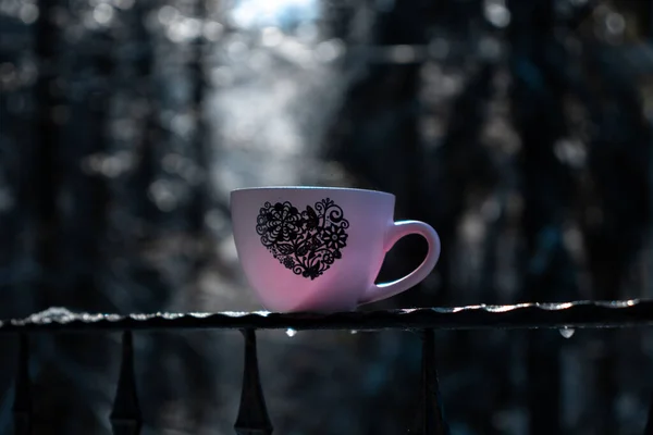 Cup of coffee with forest surroundings, snow, cold weather, mountain landscape