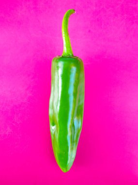 A fresh green spicy pepper. isolated on pink background.