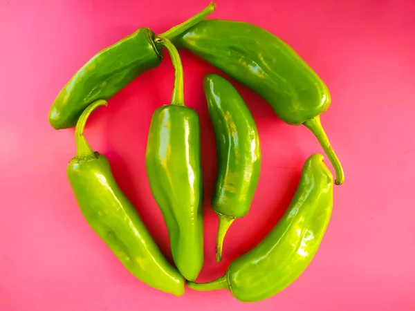 green peppers pile isolated on a pink background