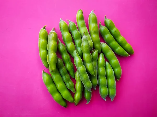 Fresh raw broad beans pods on pink background